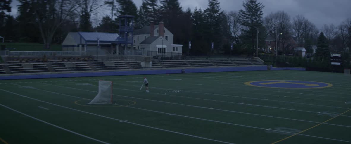 A man practices lacrosse in a field