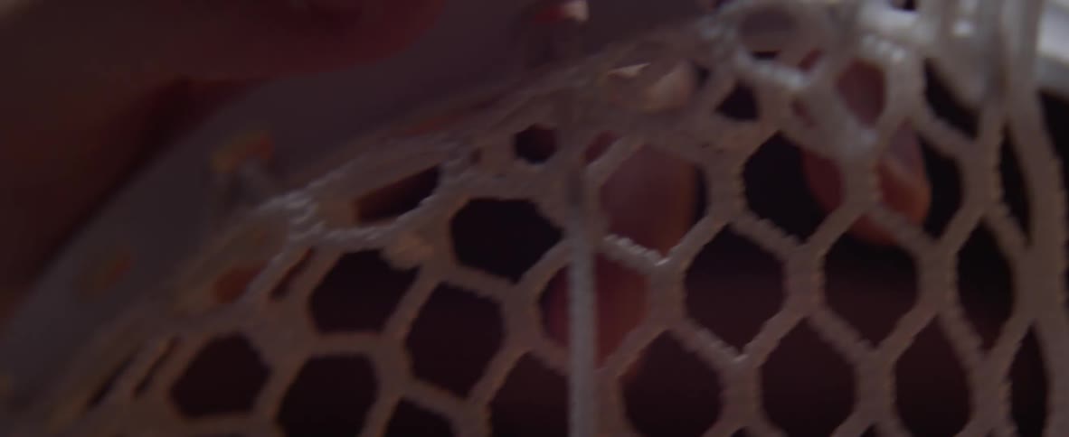 A person is attaching webbing to a frame using string and needle
