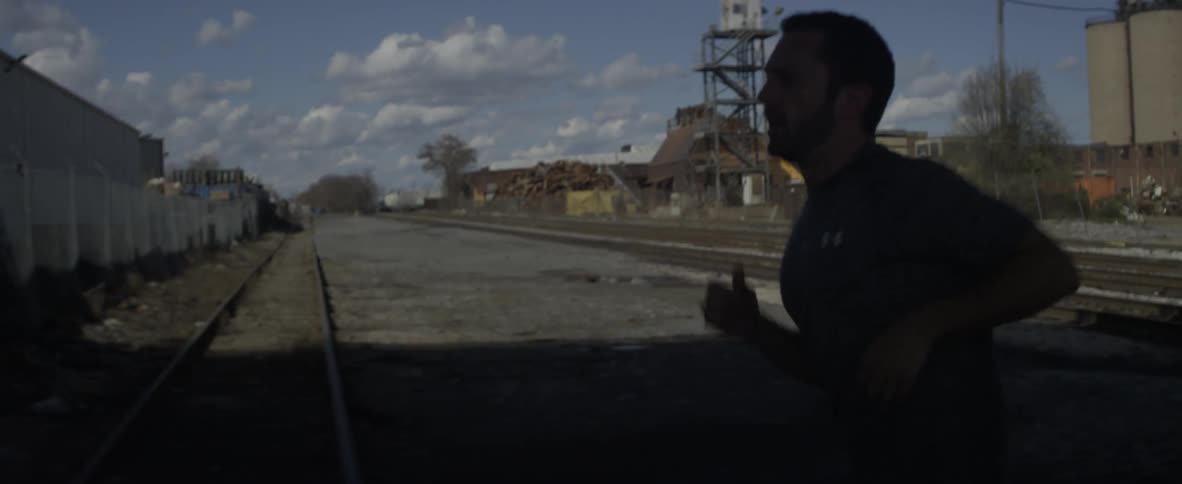 A man is jogging near train tracks