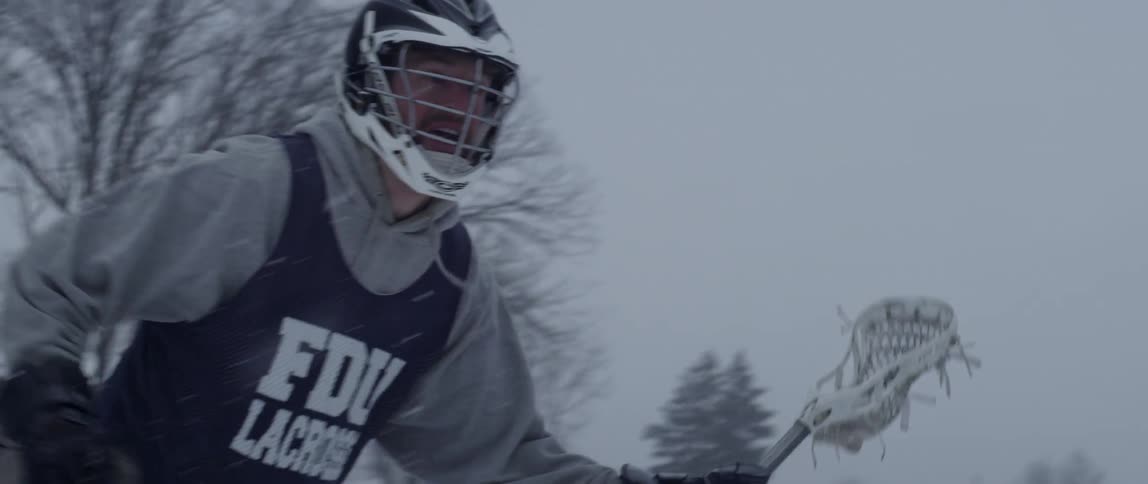 A man plays lacrosse outside while it snows