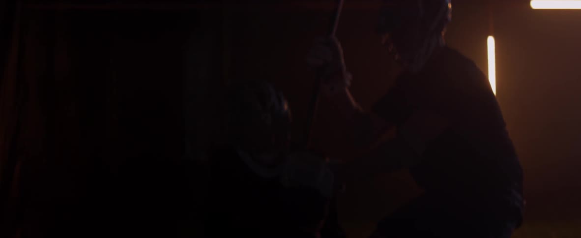 Men play lacrosse inside a dark warehouse