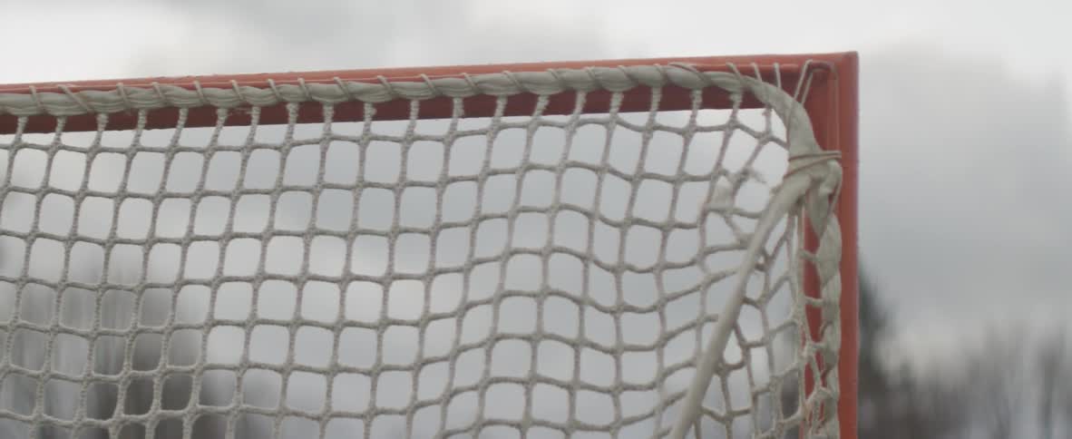 A lacrosse ball enters a net on a field