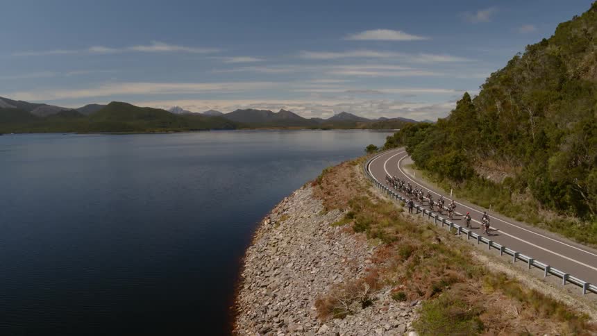 A group of bicyclists travel down a mountain road