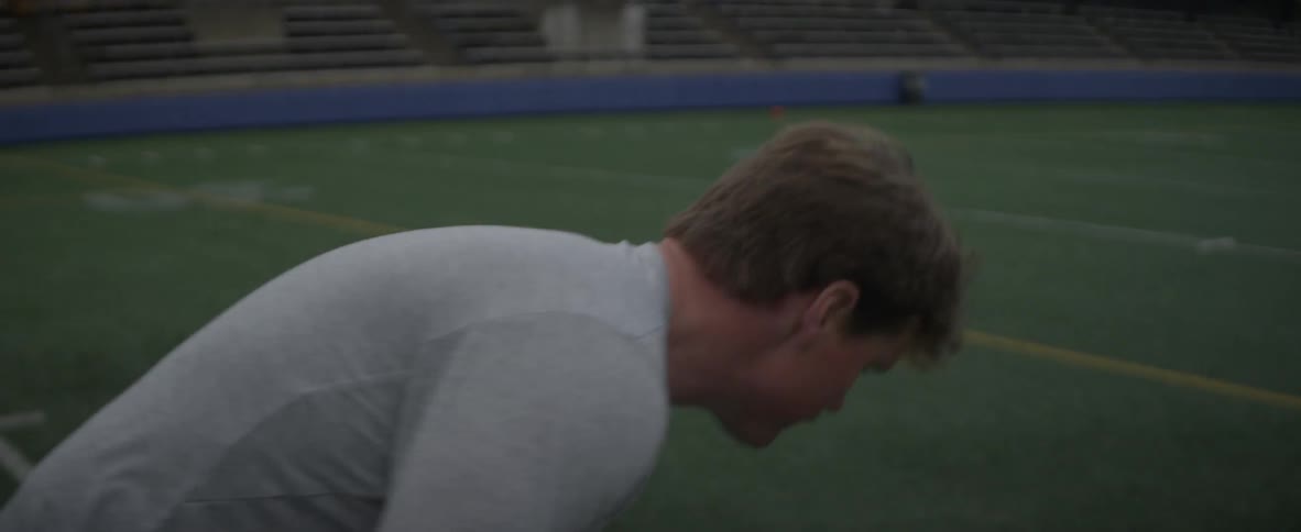 A man plays lacrosse on an athletic field