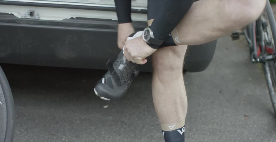 A man pulls on shoes outside