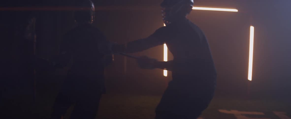 Several people play lacrosse in a dimly lit warehouse