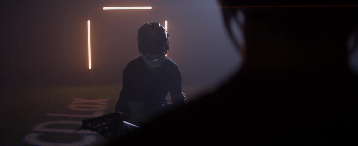 Men play lacrosse in a dark warehouse