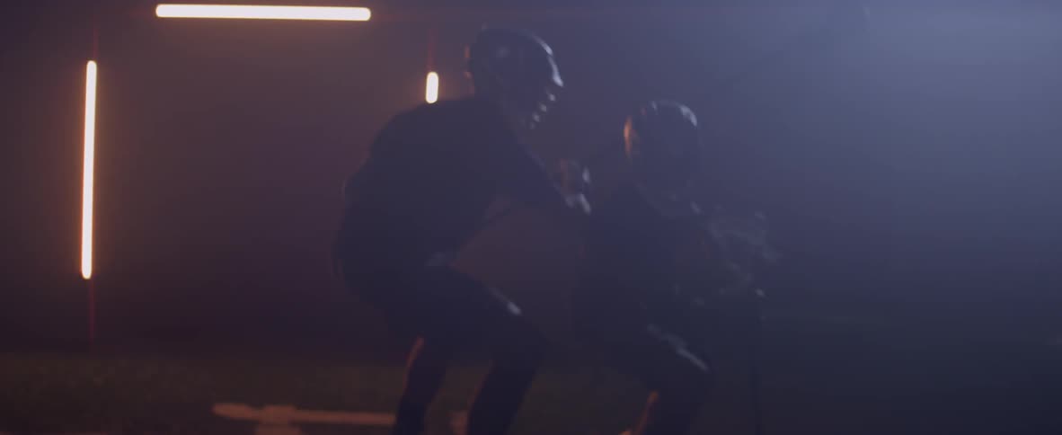 Two people are playing lacrosse indoors