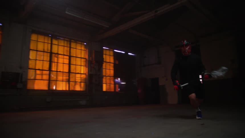 Two men are playing lacrosse indoors