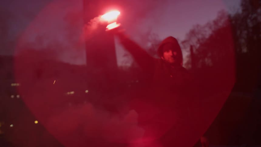 A man is standing outside waving a flare