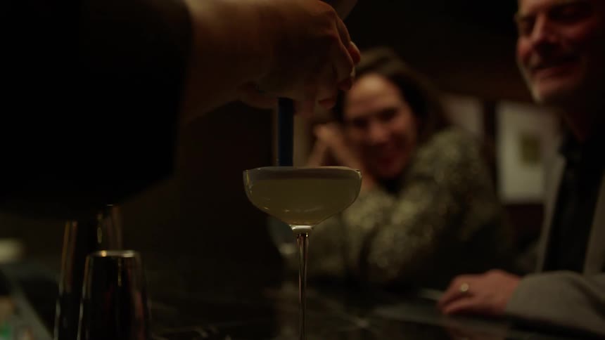 A bartender mixes a drink for patrons