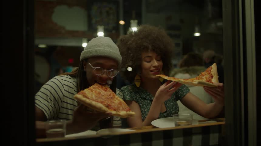 People have pizza inside of a restaurant