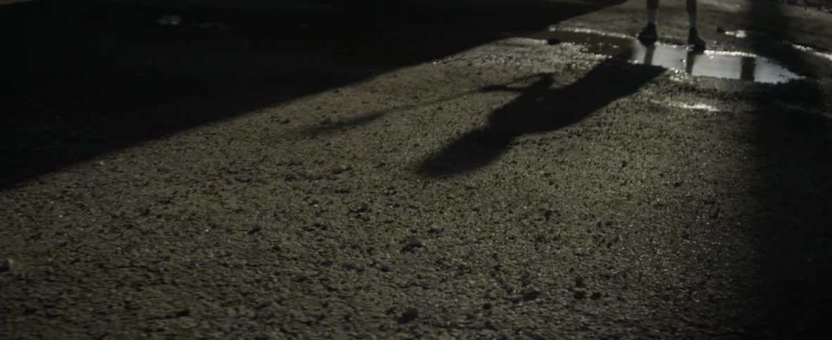 A man swinging a lacrosse stick is casting a shadow