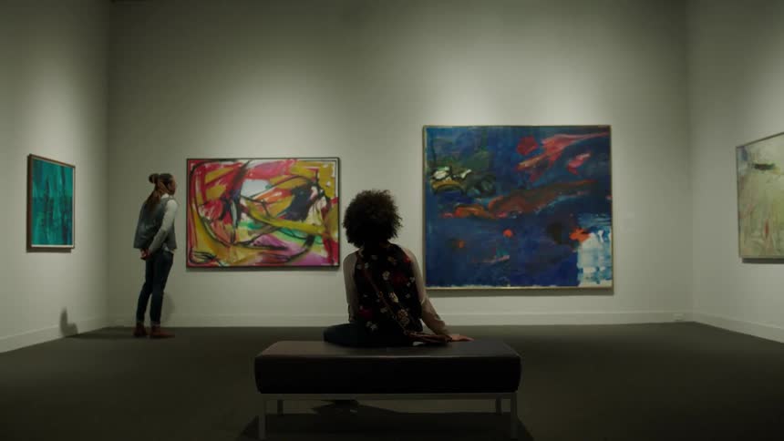 Man and woman look at paintings in a museum