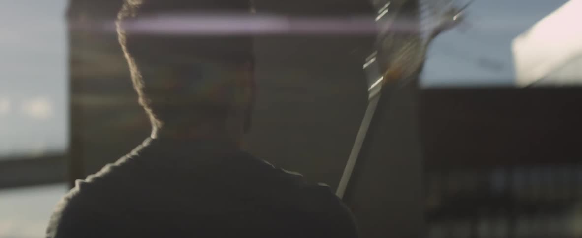 A man is repeatedly throwing a ball using a lacrosse stick