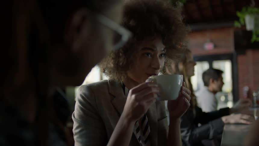 Two women are sitting at a counter having a cup of coffee