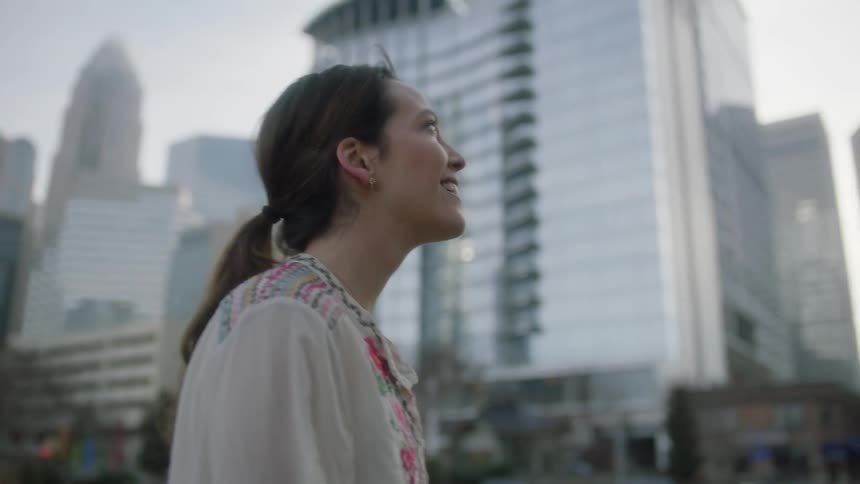 Smiling woman looks up at skyscrapers