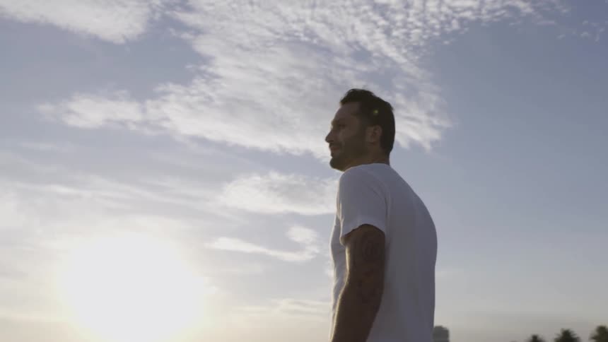 A man is standing outside on a windy day