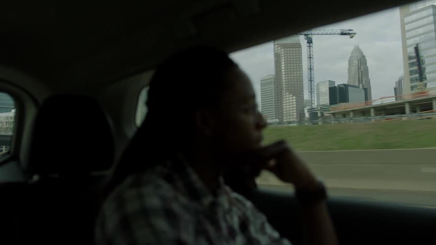 A man sitting in the back seat looks out the window
