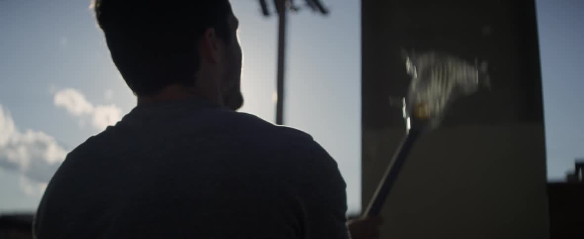 A man bounces a ball beneath a bridge and catches it with a lacrosse stick