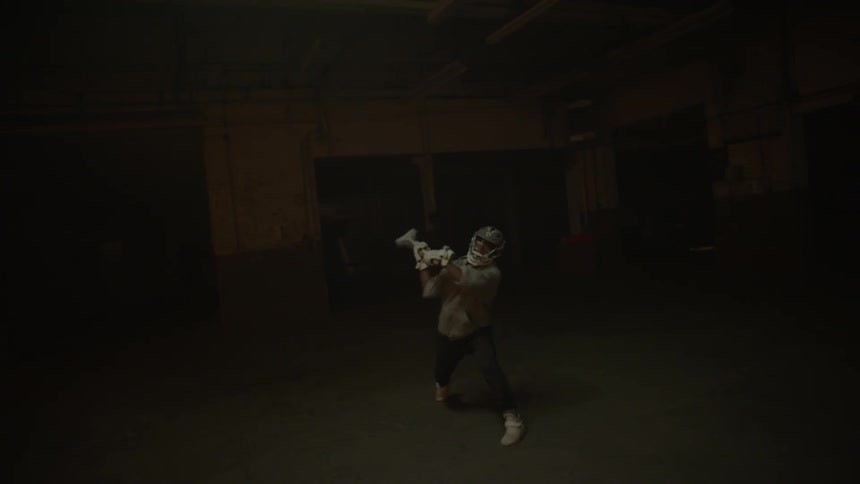 Several people play lacrosse in a dark warehouse