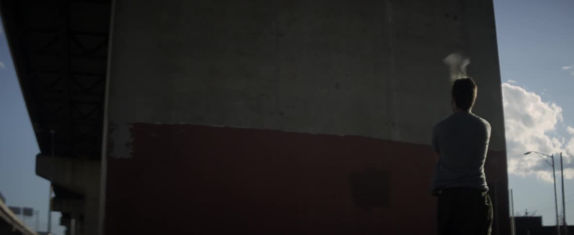 A man is tossing a ball at a wall with a lacrosse stick