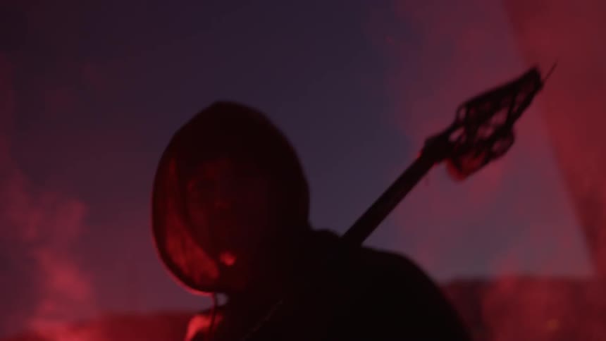 A man in a hoodie waves a red flare