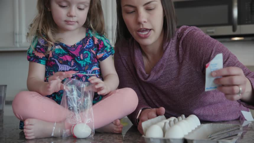 Woman and child decorate eggs together for easter