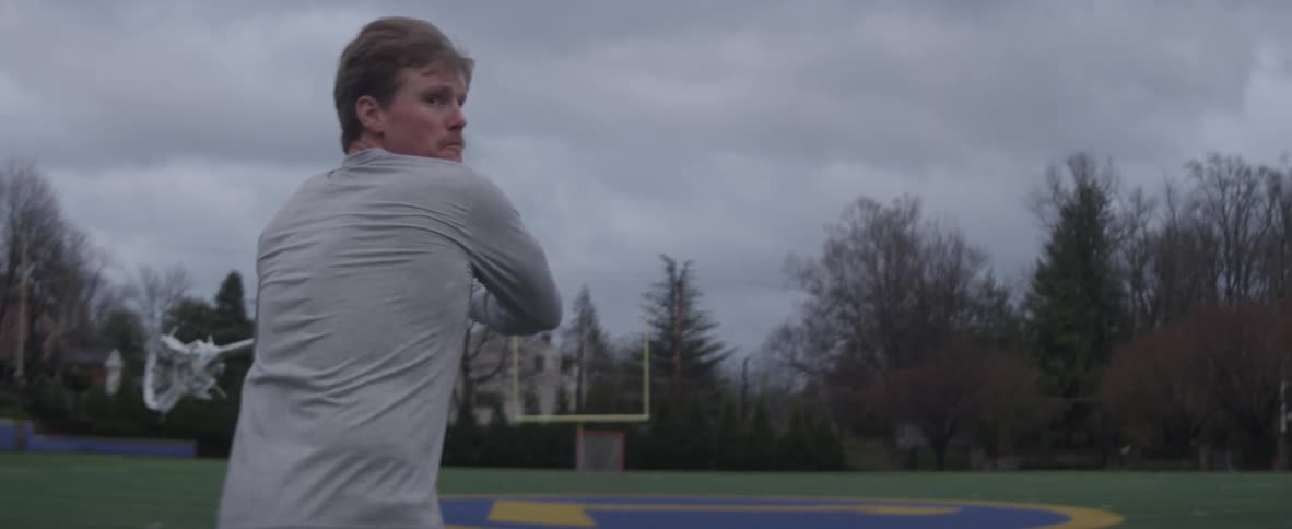 A man is practicing lacrosse
