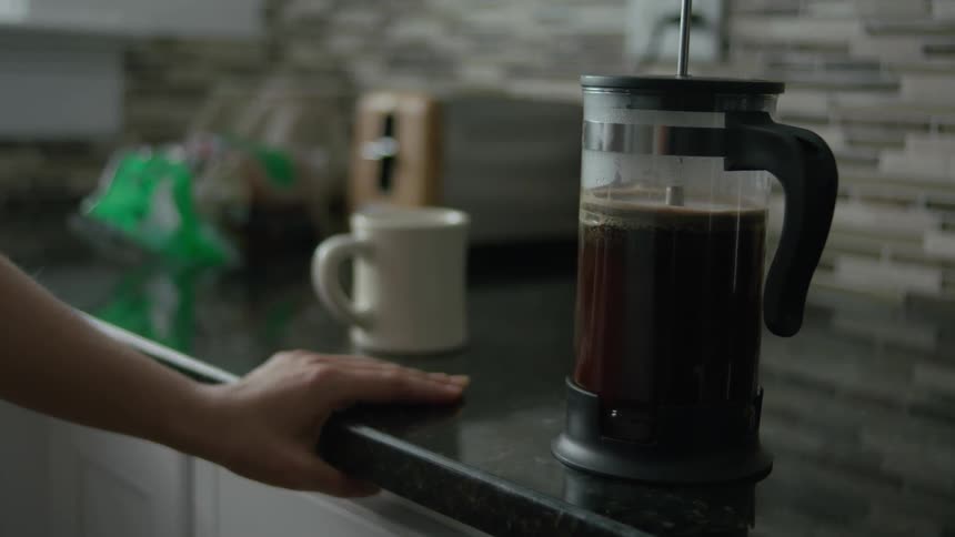 A woman uses a coffee press to make coffee