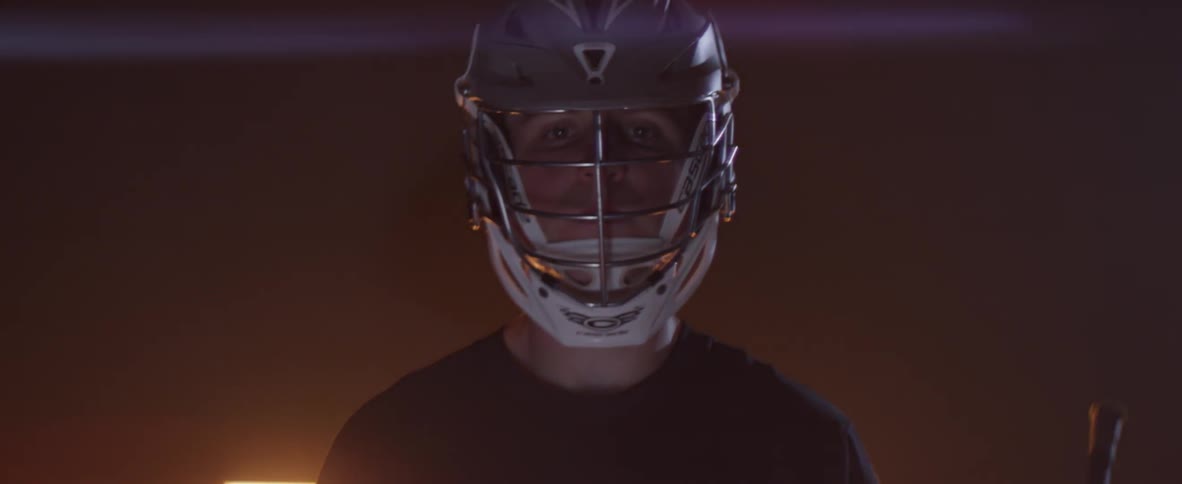 A lacrosse player stands inside a dark building