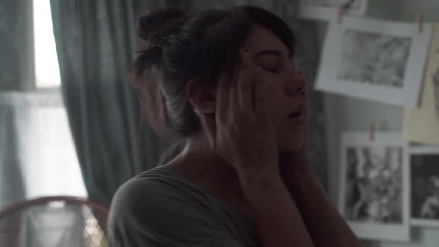Dark haired woman rubs her temples with her fingers