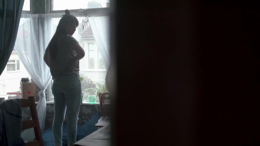 A woman looking out the window looks back briefly
