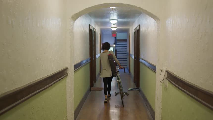 A woman pushes her bicycle down the hallway