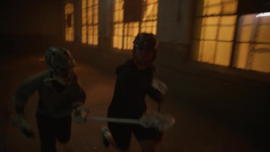Two people are playing lacrosse indoors