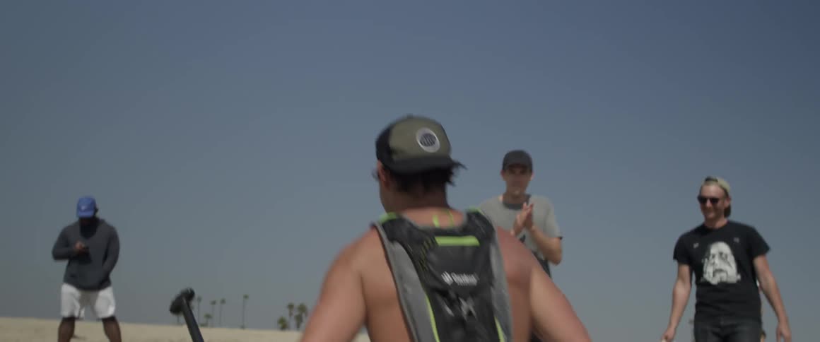 A man carries a paddle and board onto the beach