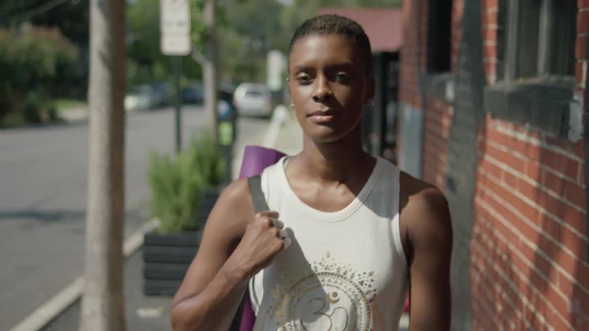 Person in a muscle shirt carrying a pink yoga mat