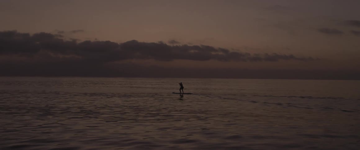 A man paddles on a board in the ocean
