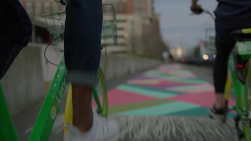 Two people ride bicycles through a city