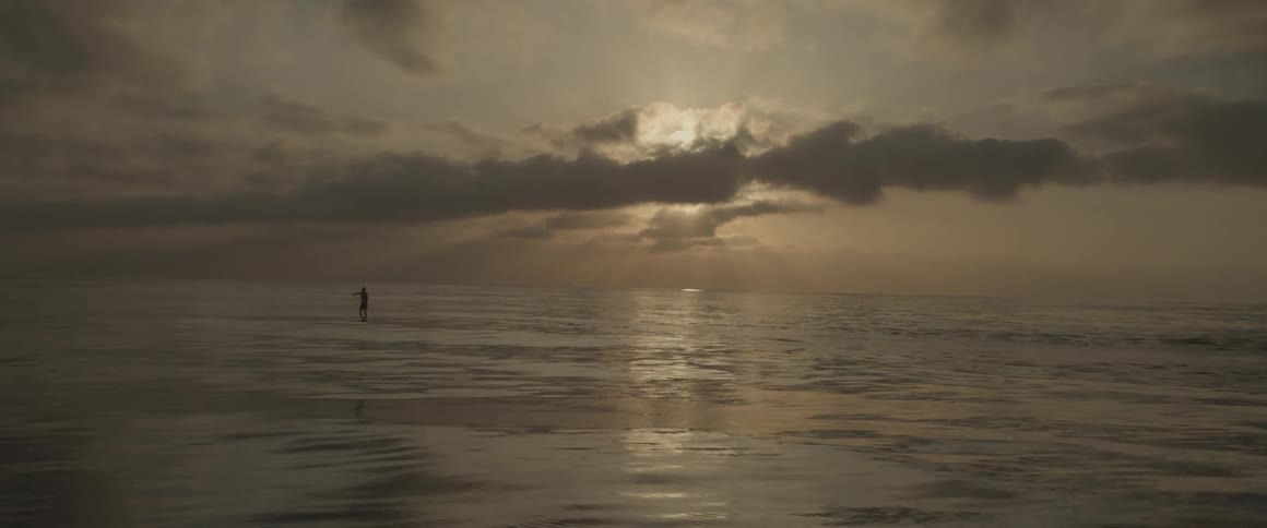 A man paddle boards on the ocean at sunset