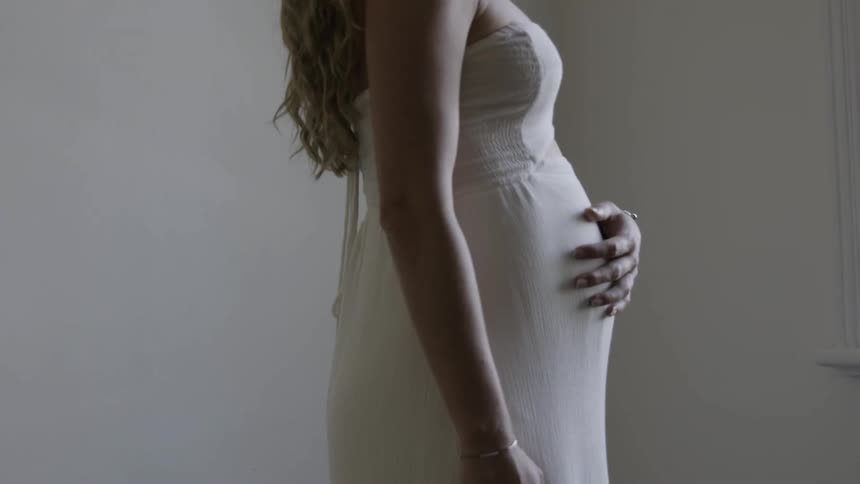 A pregnant women is walking towards a window