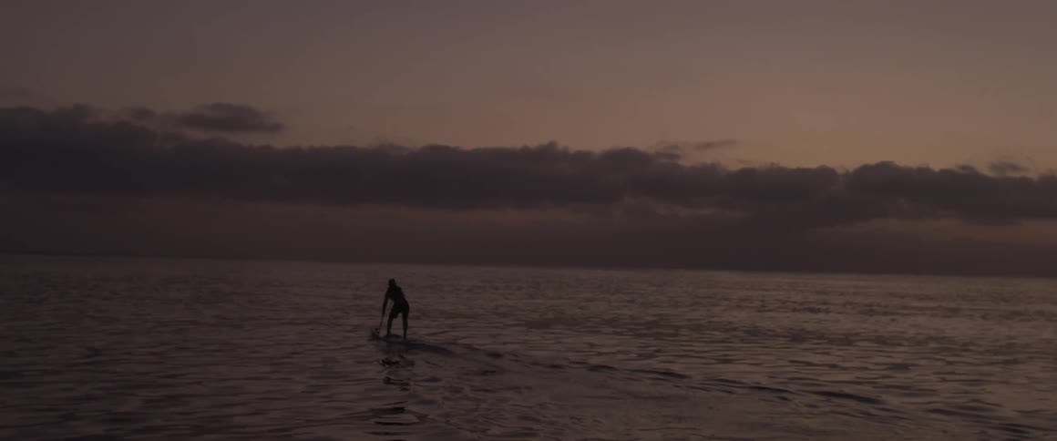 A man paddle boards on the ocean at sunset