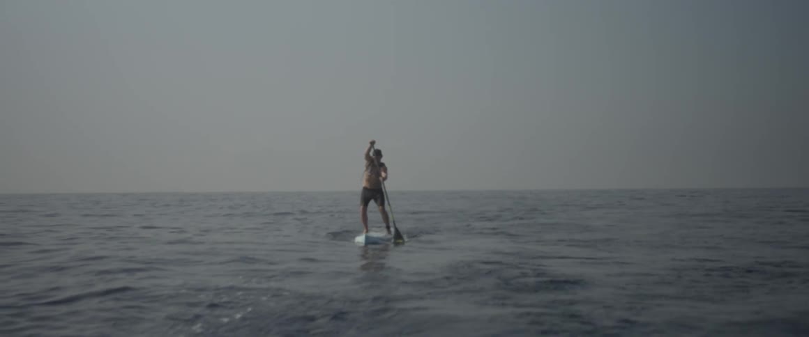A man is on the ocean paddling a stand up board
