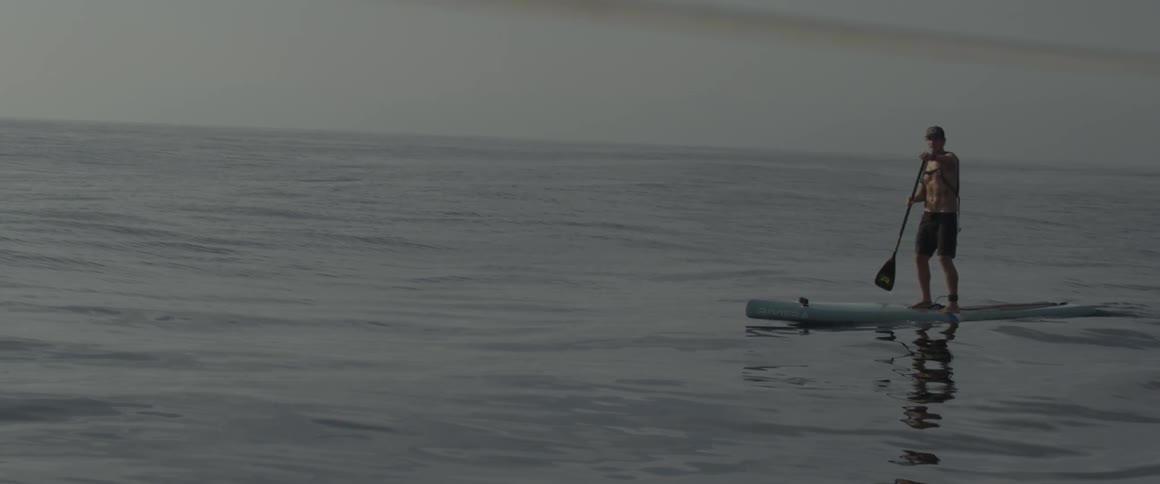 A man paddles on a board in the ocean