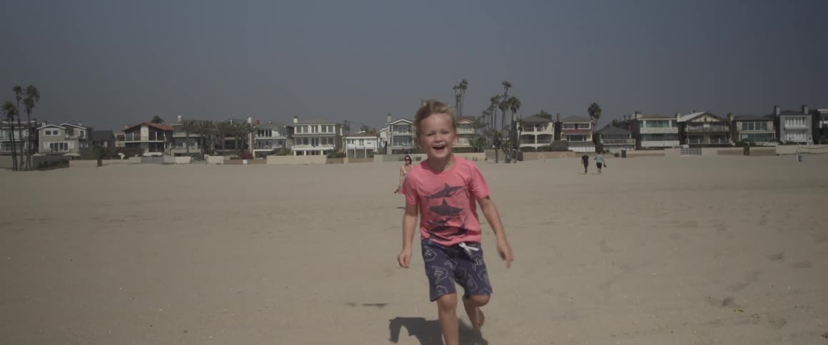 A young boy runs on a sandy beach