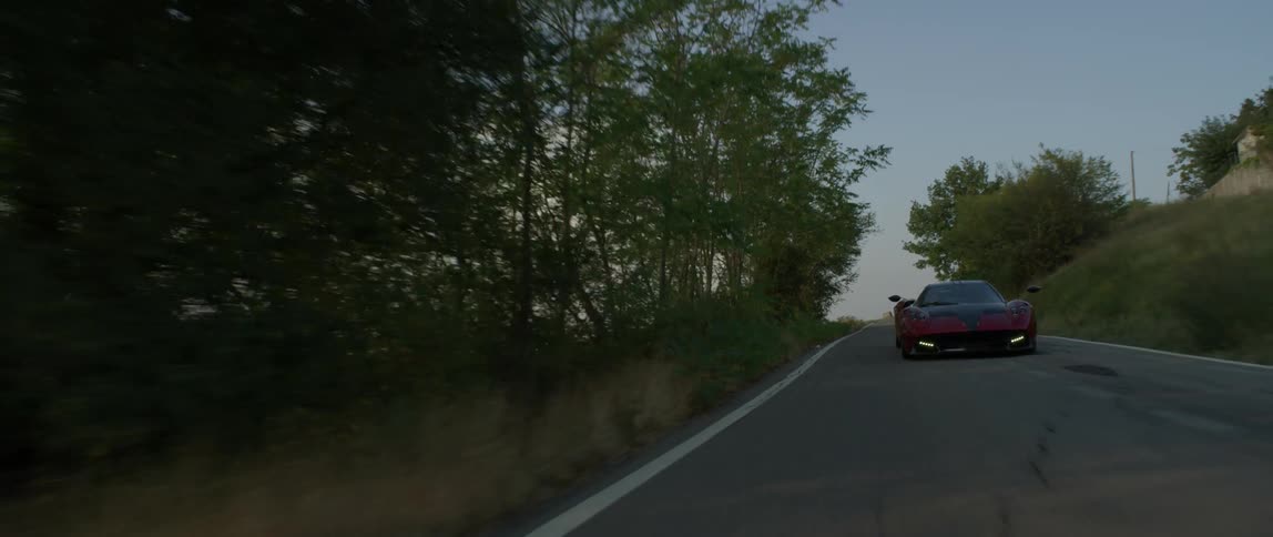 A car speeds down a hillside road