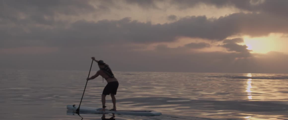 A man is paddling on his surfboard