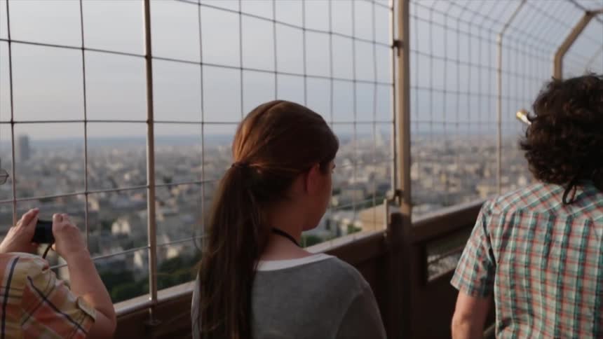 People walk around the observation deck of the Eiffel Tower