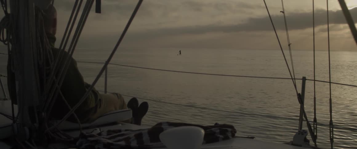 A boat sails past a person paddling on a board