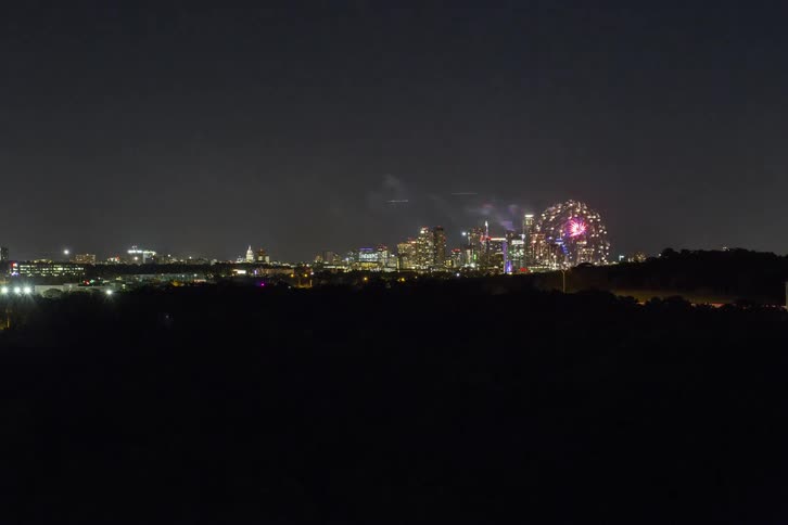 Fireworks explode over a cityscape at night